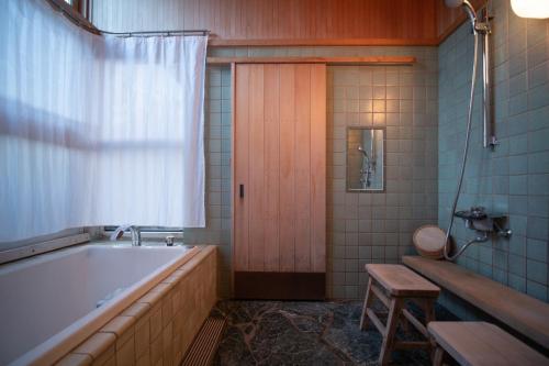 ein Badezimmer mit einer Badewanne und einer Holztür in der Unterkunft [Hida Takayama] Kiyomi-sou- - Vacation STAY 33671v in Takayama