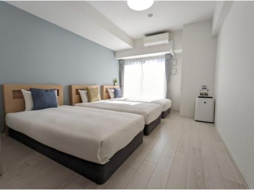 two beds in a room with white walls and a window at Eslead Hotel Namba South III - Vacation STAY 39768v in Osaka