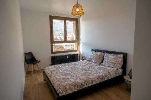 een slaapkamer met een bed, een raam en een stoel bij Appartement vue montagnes in Gap