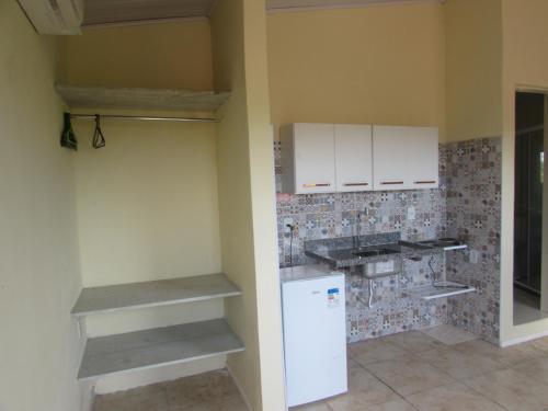 eine Küche mit weißen Schränken und einem weißen Kühlschrank in der Unterkunft Sítio Colina Eventos in Santo Antônio do Rio das Pedras