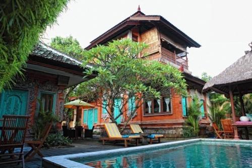 a house with a swimming pool in front of a house at Sunhouse Guesthouse in Sanur