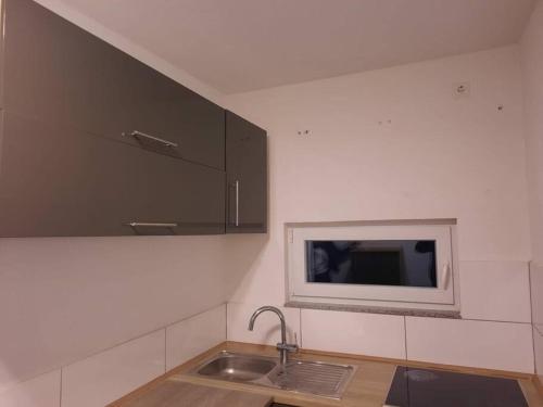 a kitchen with a sink and a tv on the wall at Wohnen wie Zuhause in Abstatt