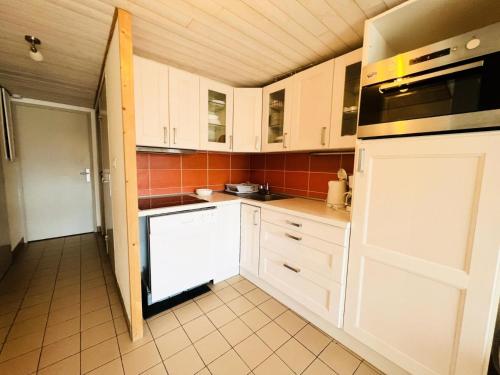 une cuisine avec des armoires blanches et un four à plaques de cuisson dans l'établissement Green Village - Deux pièces mezzanine résidence avec piscine MAE-2004, à La Grande Motte