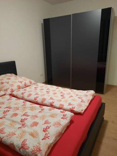 a bed with a red blanket on top of it at Wohnen wie Zuhause in Abstatt