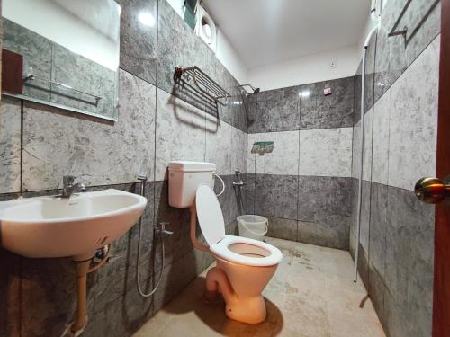 a bathroom with a toilet and a sink at Crown Hotel in Tiruvannāmalai