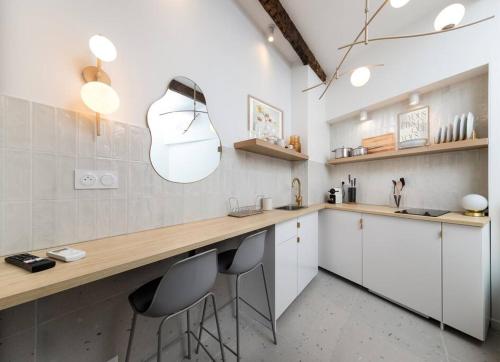 une cuisine avec des armoires blanches et un comptoir avec des tabourets dans l'établissement Unique Old Town Designer Studio, à Nice