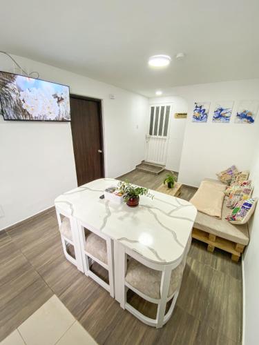 Habitación con baño compartido في بوغوتا: غرفة معيشة مع طاولة بيضاء وأريكة