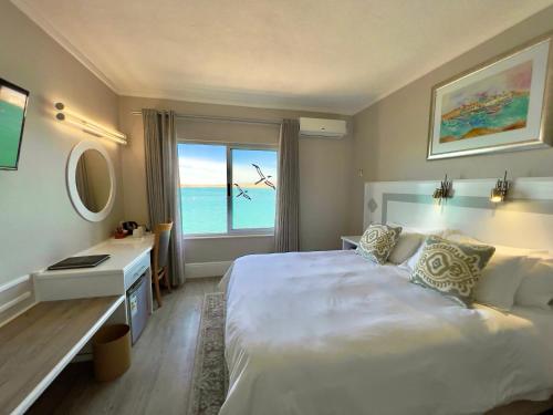 Lüderitz Nest Hotel في لودريتز: غرفة نوم بسرير ومكتب ونافذة