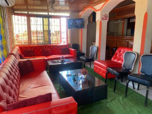 uma sala de estar com sofás vermelhos e cadeiras em Clientèle Hotel em Cabo Haitiano