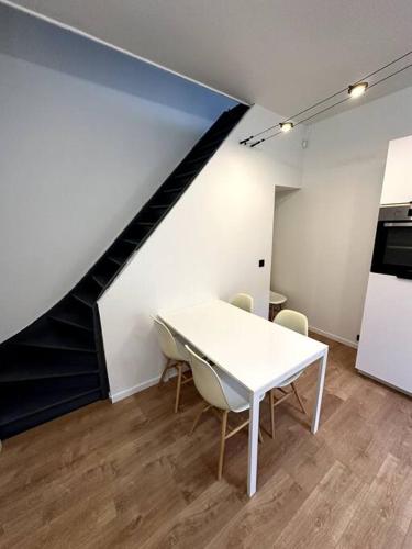 une table et des chaises blanches dans une pièce avec un escalier dans l'établissement Maison fraichement rénové, à Lille