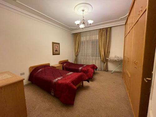 a bedroom with two beds with red comforters at Comfortable family apt - 1002 in Amman