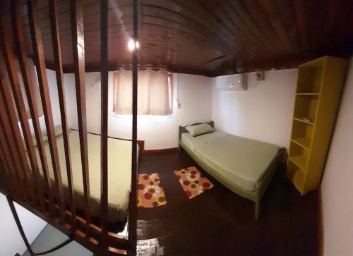 um pequeno quarto com uma cama e uma estante de livros em Home La Pampa em Puerto Iguazú