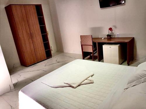 a bedroom with a bed with a wooden cabinet and a table at HOTEL ELDORADO ECONOMIC in Paracatu