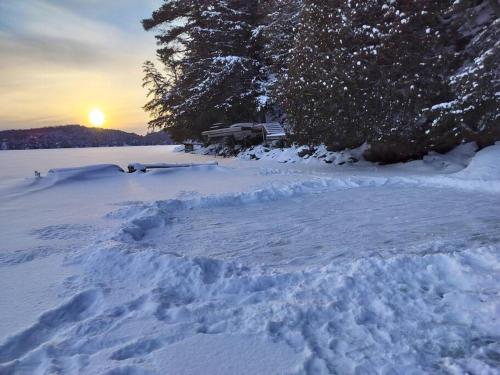 a pile of snow with the sun setting in the background at The Bear Cave Cottage at Little Kennisis Lake in Algonquin Highlands