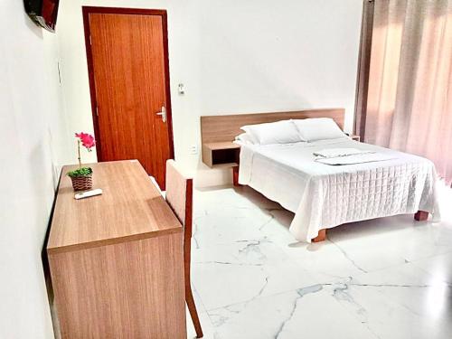 - une chambre avec un lit et une table en bois dans l'établissement HOTEL ELDORADO ECONOMIC, à Paracatu