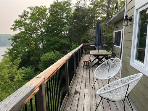 a wooden deck with two chairs and an umbrella at The Bear Cave Cottage at Little Kennisis Lake in Algonquin Highlands