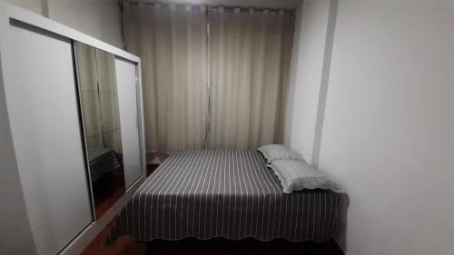 een kleine slaapkamer met een bed en een spiegel bij studio in Rio de Janeiro