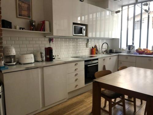 a kitchen with white cabinets and a table with a tableablish at Loft 50m2 entre la Seine et le Panthéon in Paris