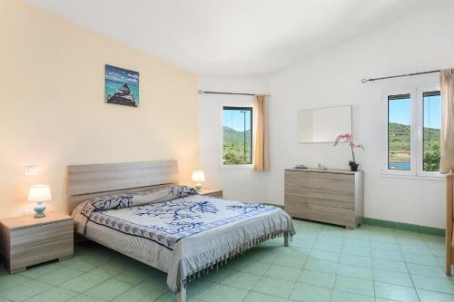 a bedroom with a bed and two dressers and two windows at Vista mozzafiato fronte mare in Olbia