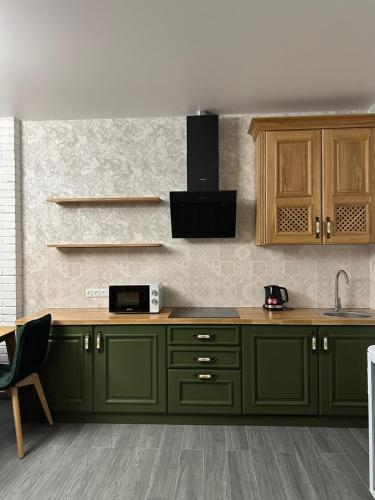 a kitchen with green cabinets and a counter at Sinay Hotel & Restaurant in Chechel'nyk