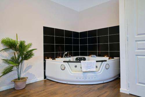 a bath tub in a bathroom with a plant at NG Prestige - Nain - Suite Spa Privatif - Jacuzzi - Netflix - Projecteur in Roubaix
