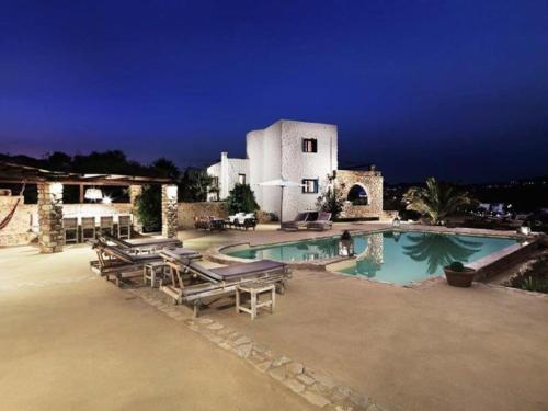 a resort with a swimming pool with chairs and a building at Villa Icarus, Private Luxury Villa in Kampos Paros