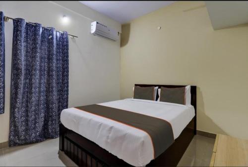 a bedroom with a large bed with blue curtains at SS Suites in Bengaluru
