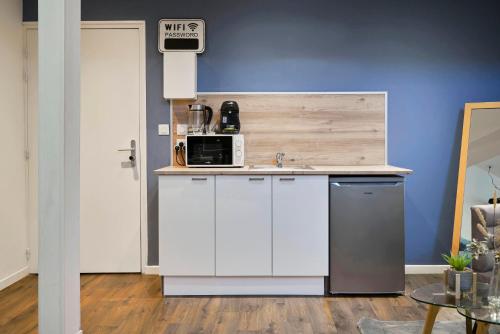 a white kitchen with a sink and a microwave at NG Prestige - Nain - Suite Spa Privatif - Jacuzzi - Netflix - Projecteur in Roubaix