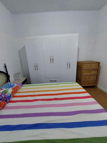 a bedroom with a bed with a colorful striped blanket at Cantinho das Olandas in Olinda