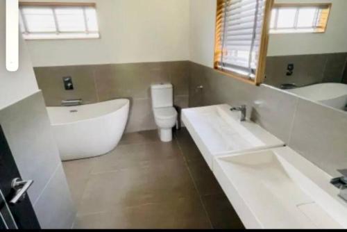 a bathroom with a tub and a toilet and a sink at Lush Lodge 