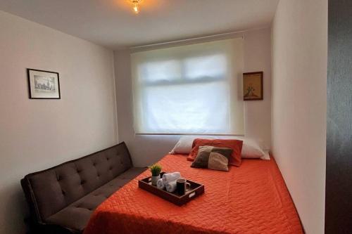 ein Schlafzimmer mit einem Bett mit einer orangefarbenen Decke und einem Fenster in der Unterkunft Apartamento en centro Ciudad de Guatemala z12 in Guatemala