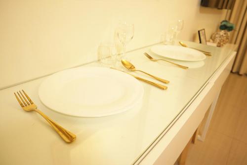 a table with two white plates and gold utensils at Homefort at Shore Residences in Manila