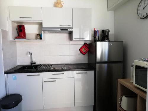 une cuisine avec des armoires blanches et un réfrigérateur en acier inoxydable dans l'établissement Résidence Le Chateau Durieux 1 - Agréable studio au coeur des commerces ! MAE-4104, à Aix-les-Bains