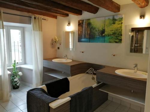 ein Badezimmer mit zwei Waschbecken, einer Badewanne und zwei Spiegeln in der Unterkunft gite de la Marzelle in Saint-Sulpice-des-Landes