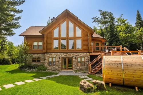 a log home with a large window at Chalet Red Deer Spa at Fiddler Lake in Mille-Isles