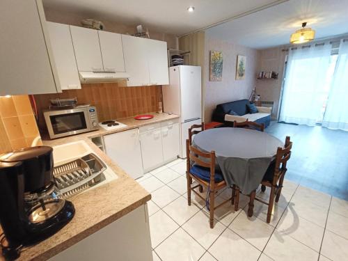 une cuisine avec une table et une petite cuisine avec une salle à manger dans l'établissement Résidence Le Vendome - Agréable T2 dans quartier animé à proximité des commerces ! MAE-6704, à Aix-les-Bains