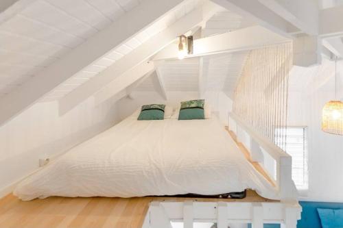 een slaapkamer met een wit bed op de zolder bij Ticase, charmante maisonnette idéalement située in Saint Martin