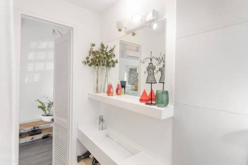 een witte badkamer met witte planken en een spiegel bij Ticase, charmante maisonnette idéalement située in Saint Martin