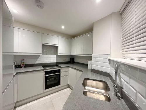 una cocina con armarios blancos y fregadero en Modern apartment in high street location. en Midsomer Norton