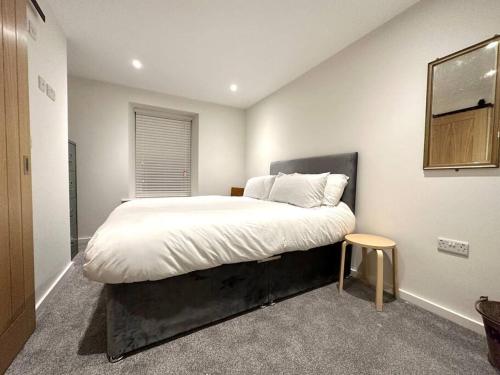 a bedroom with a large bed with white sheets at Modern apartment in high street location. in Midsomer Norton