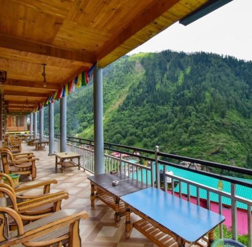 a balcony with tables and chairs and a view of a mountain at Pahadi Bliss Hostel ,Tosh in Tosh
