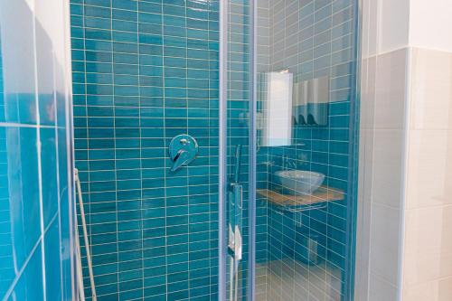 - une douche carrelée de bleu avec une porte en verre dans l'établissement Resort Acqua di Venere, à Paestum