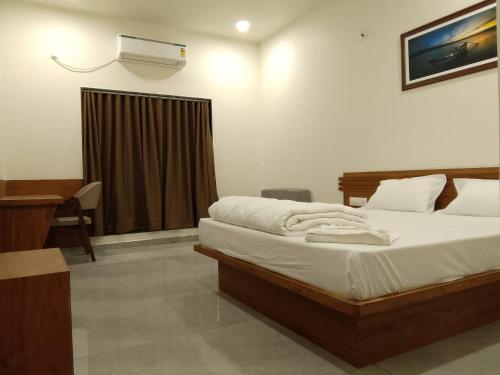 a bedroom with a bed and a desk and a air conditioner at The Grand Dharti in Kodīnar