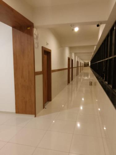 un corridoio vuoto con porte in legno e pavimento piastrellato bianco di The Grand Dharti a Kodīnar