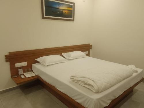 Bett mit weißer Bettwäsche und Kissen in einem Zimmer in der Unterkunft The Grand Dharti in Kodīnar