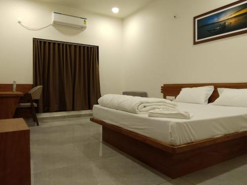 a bedroom with a bed and a desk with a air conditioner at The Grand Dharti in Kodīnar