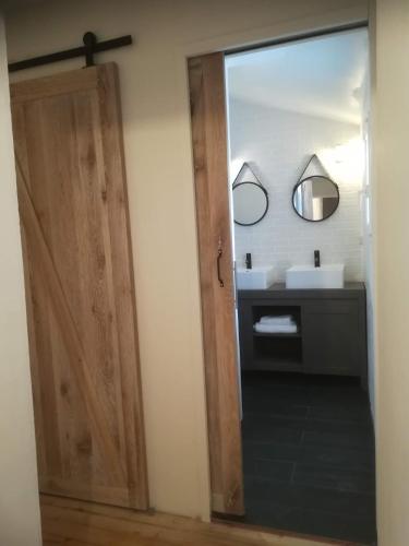 une porte de salle de bain avec un lavabo et un miroir dans l'établissement La Longère de Fréd et Line, à La Garnache