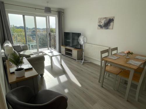 a living room with a table and a living room with a television at Balcony Apartment - Views Of Etihad Stadium - Near CoOp Live Arena in Manchester