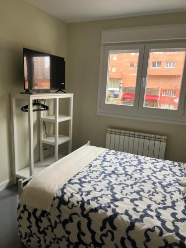 a bedroom with a bed and a flat screen tv at ApartaSoles in Valladolid