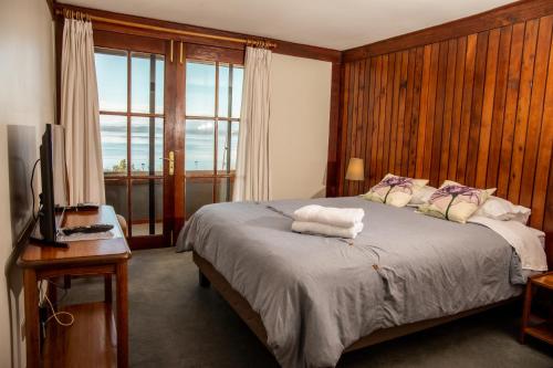 a bedroom with a bed with a television and a window at Hotel Hosteria Entre Lagos in Puyehue